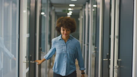 happy young businesswoman coming out of office celebrating in corridor