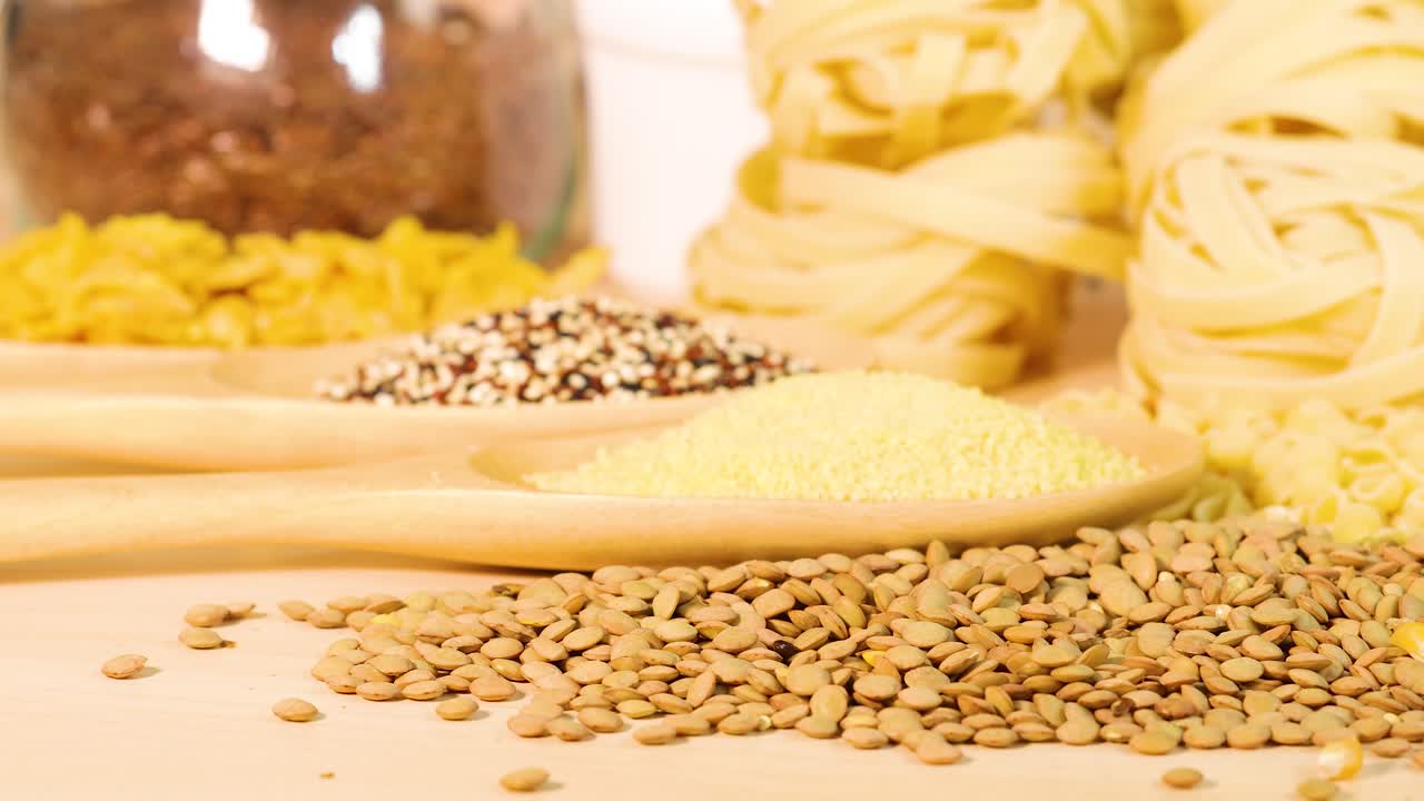 Close-up of various grains and pasta on a wooden surface with soft lighting and a warm, inviting atmosphere