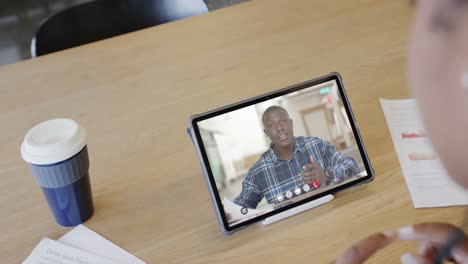 Caucasian-businesswoman-on-tablet-video-call-with-african-american-male-colleague-on-screen