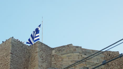 greek flag waving atop an ancient stone fortress