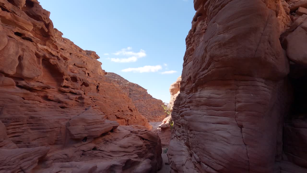 Veduta di un canyon con pareti di arenaria rossa, inclinazione verso il basso per rivelare uno stretto passaggio
