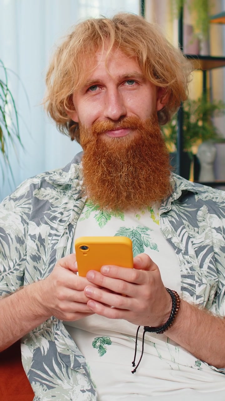 Caucasian young man sitting on sofa using smartphone share messages on social media application