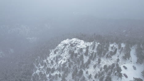 drone aerial footage flying over snowcapped rocky peak in flatirons mountain boulder colorado usa