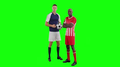 video of two diverse male soccer players with ball on green screen background