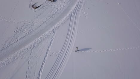 Smooth-spiral-aerial-footage-of-young-blonde-girl-walking-through-snow