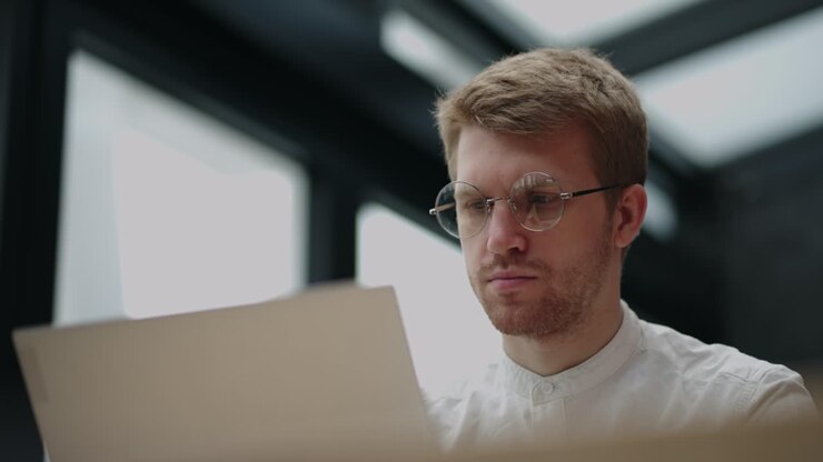 office of modern company, handsome adult man is working with laptop, creative designer or programmer