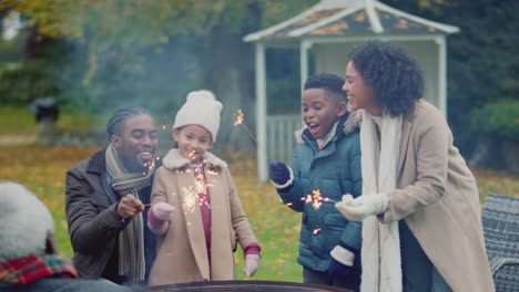 family having fun with sparklers in autumn garden at home - shot in slow motion