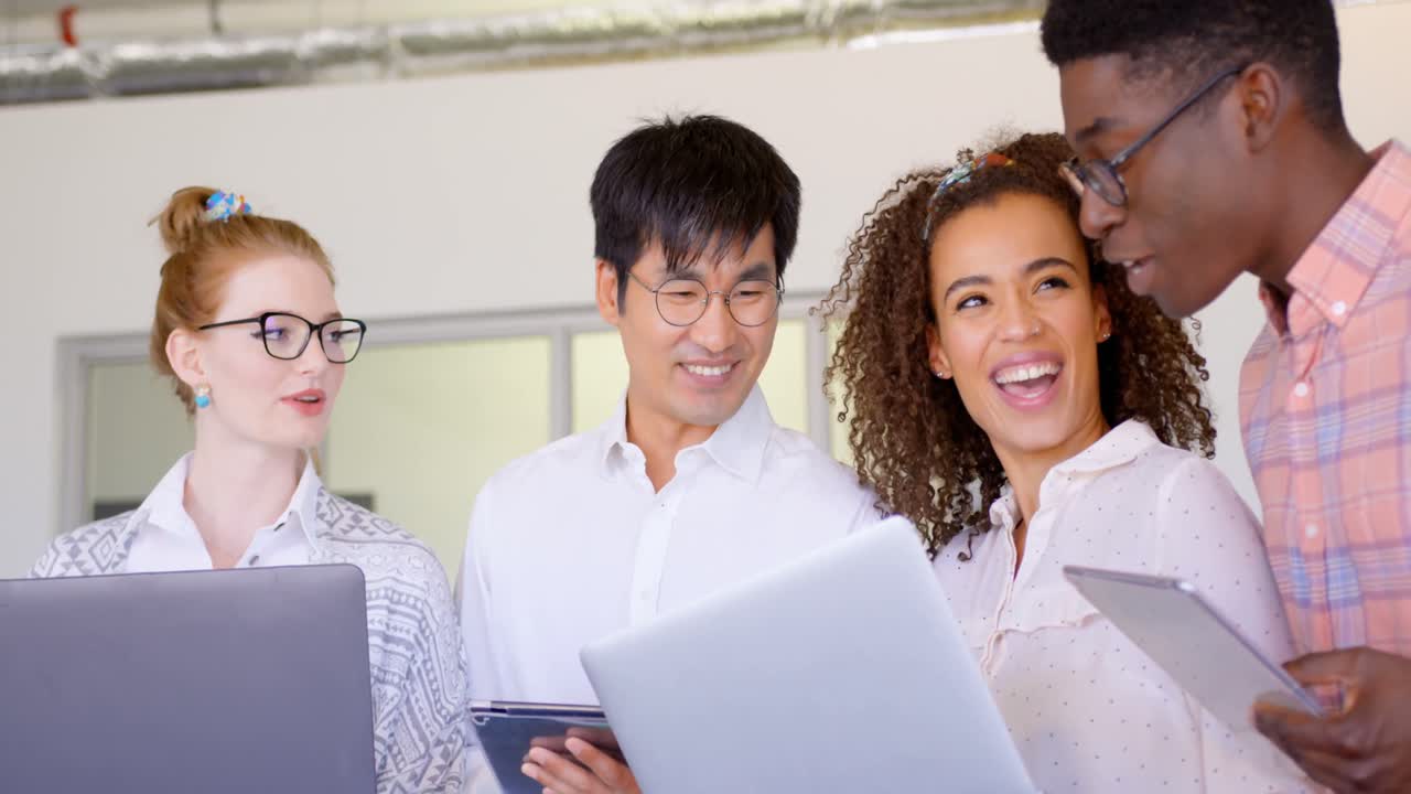 Multi-ethnic business people discussing over laptop and digital tablet in modern office 4k