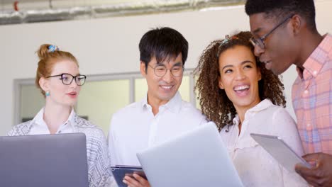 Multi-ethnic-business-people-discussing-over-laptop-and-digital-tablet-in-modern-office-4k