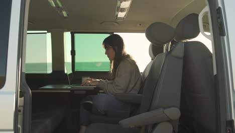 traveling woman working on laptop in van