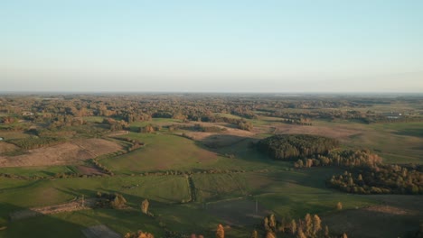 aerial: vast green fields and forest with golden blue sky over horizon