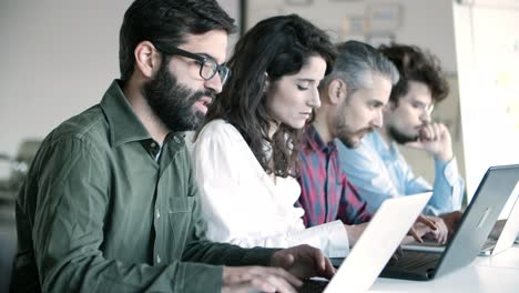 Side-view-of-concentrated-programmers-working-with-laptops