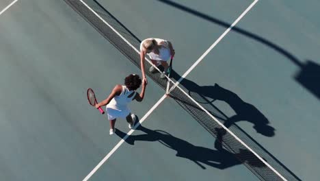 Video-of-top-view-of-diverse-female-tennis-players-on-court,-shaking-hands