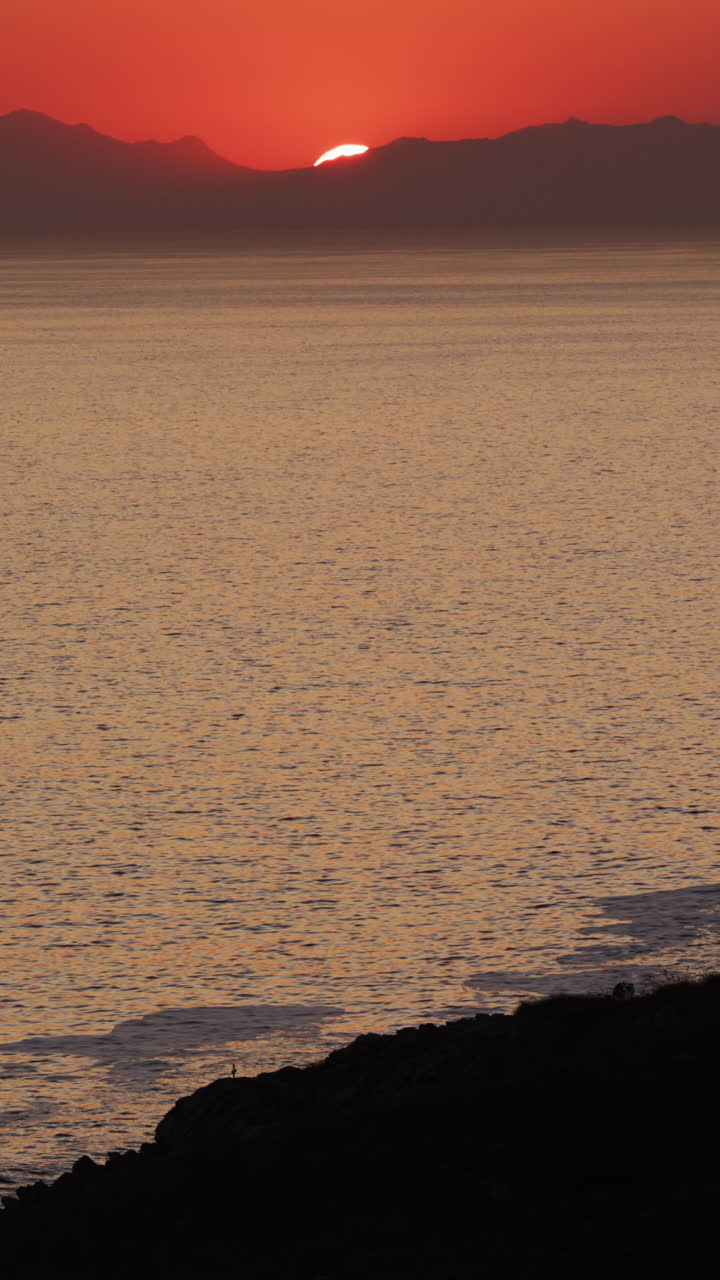 video vertical de la hermosa vista del atardecer sobre la costa rocosa