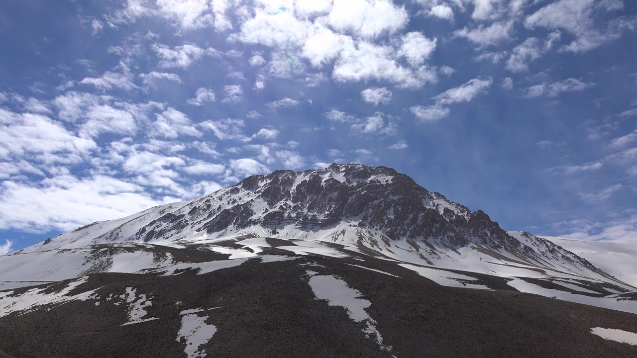 Cima di montagna innevata sotto un cielo blu con nuvole