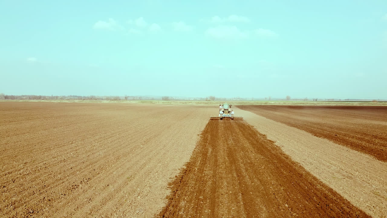 Tractor operates across wide agricultural fields, high angle shot