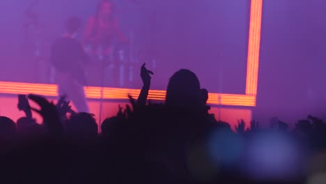 people dancing with hands in the air at music event with lights show