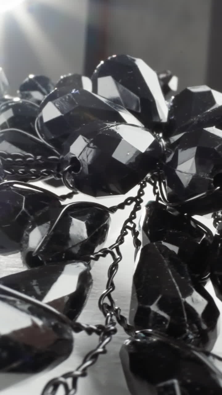 Glistening black beaded necklace with a sunburst flare on a glossy white surface