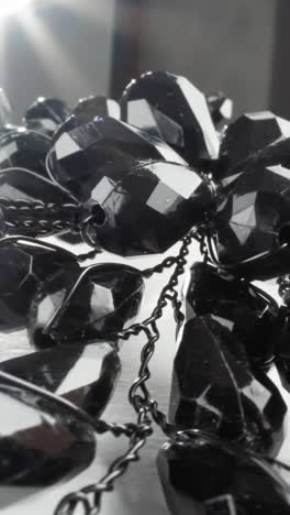 collar de cuentas negras brillantes con una llamarada de sol en una superficie blanca brillante