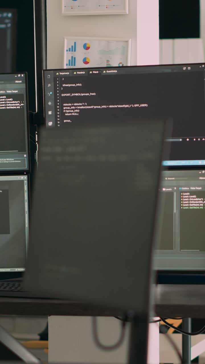 Vertical video: Computer screens on desk running programming code data algorithms