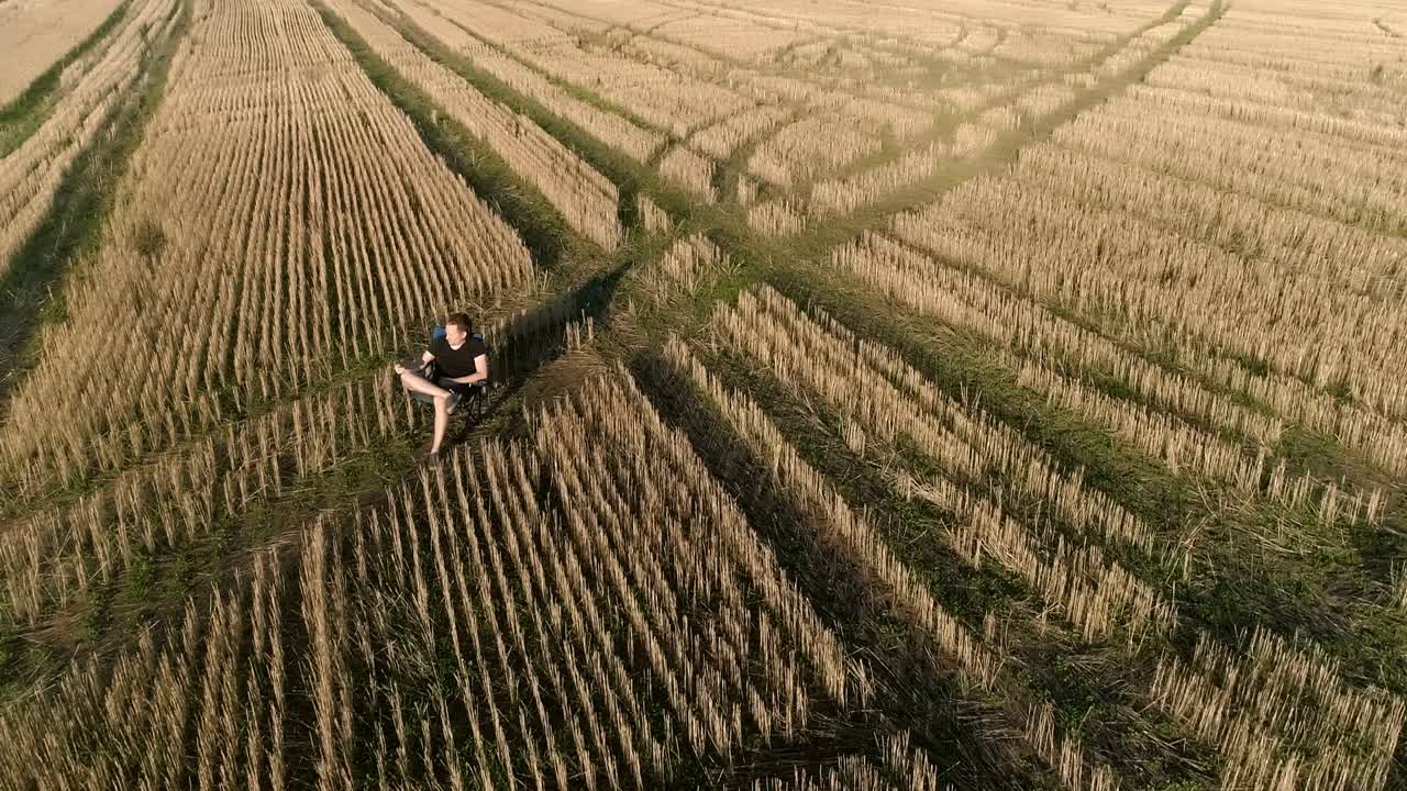 한 남자가 시골에서 휴식을 취하고, 한 젊은이가 에서 의자에 앉아 전화를 하고 있다.