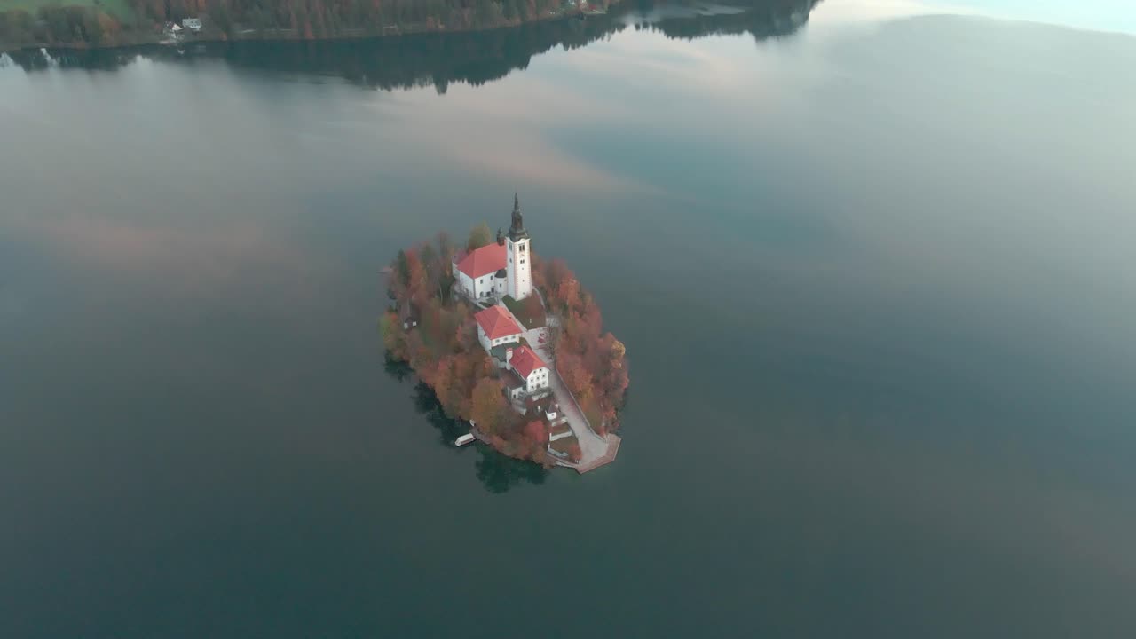 L'isola del lago di Bled in Slovenia con il drone che vola verso l'isola e abbassa la telecamera sull'isola stessa di prima mattina