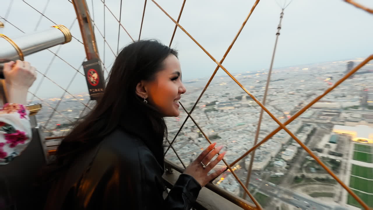Bellissima giovane donna bruna che ammira il panorama urbano di Parigi dalla Torre Eiffel, Francia, al tramonto