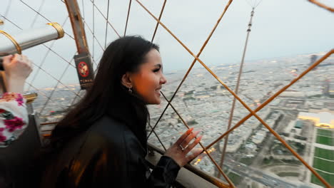 Beautiful-young-brunette-woman-looking-at-Paris-cityscape-from-the-Tour-Eiffel,-France,-at-dusk