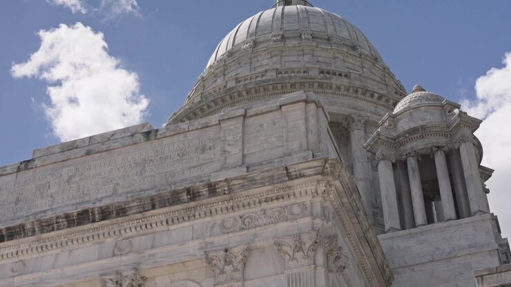 Inquadratura cinematografica che rivela il Campidoglio del Rhode Island incorniciato da un lampione decorativo con l'iconica cupola in marmo che si erge maestosa a Providence, Rhode Island