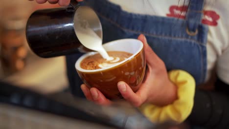 Weiblicher-Barista-Gießt-Strommilch,-Die-Latte-Art-Im-Café-Macht,-Zeitlupe