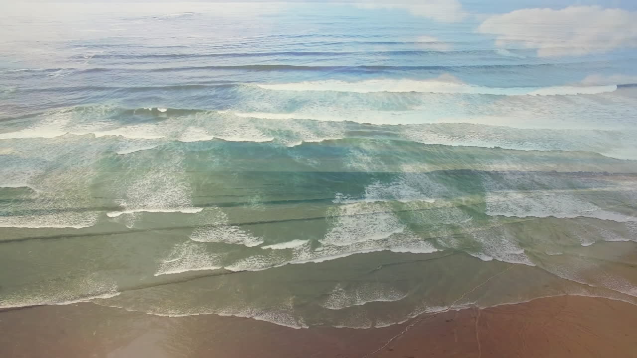 Waves crashing on sandy beach with clear blue sky in background