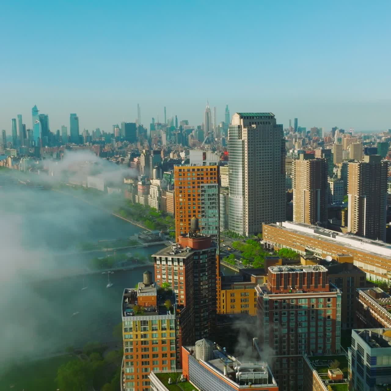 Stunning skyline of Manhattan Island sunlit in the morning. White fog coming from the water to the city buildings