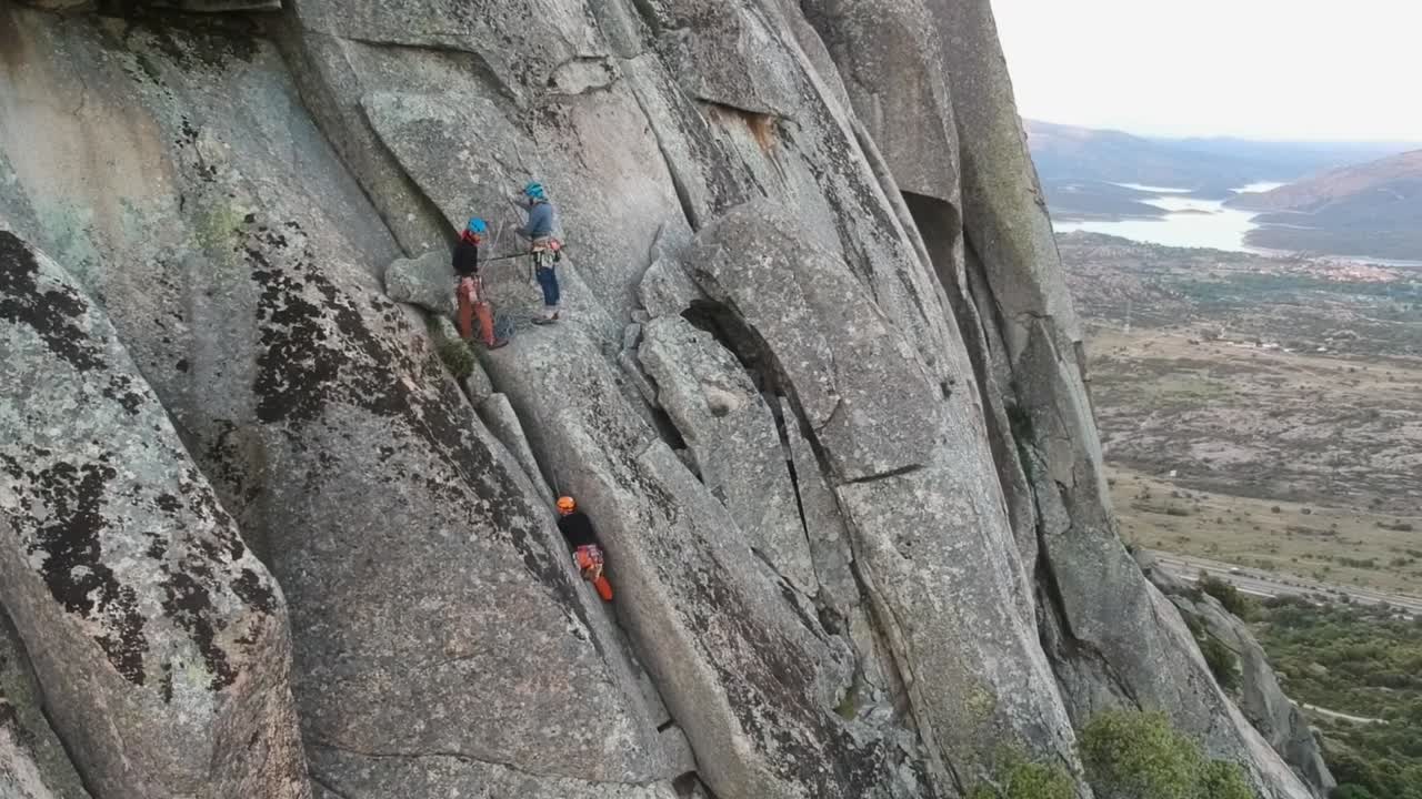 Aerial shot rotating over some climbers on a granite wall, revealing the landscape