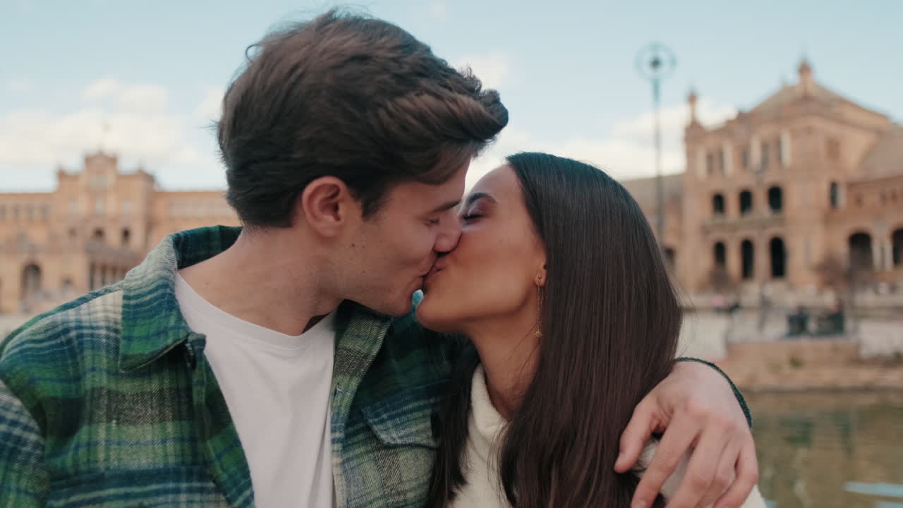 Primo piano di due giovani partner felici, un uomo e una donna, che si abbracciano e si baciano mentre sono in piedi