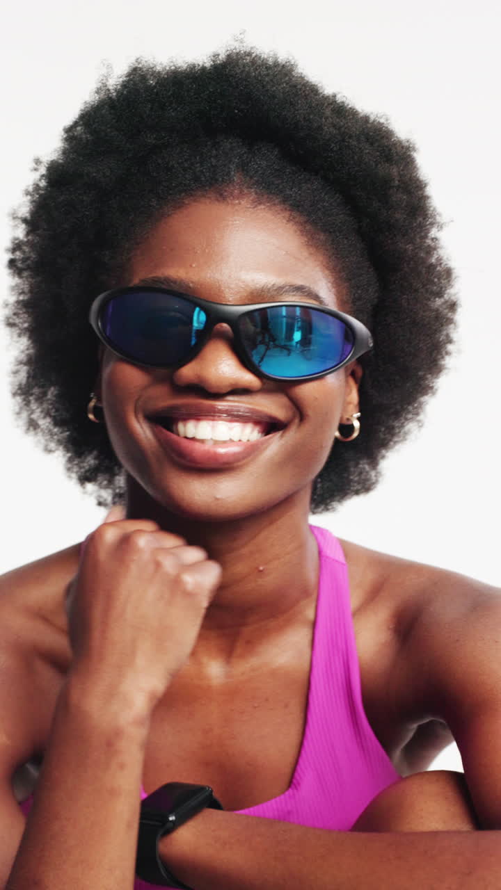 Giovane donna nera sorridente in posa con occhiali da sole sportivi.