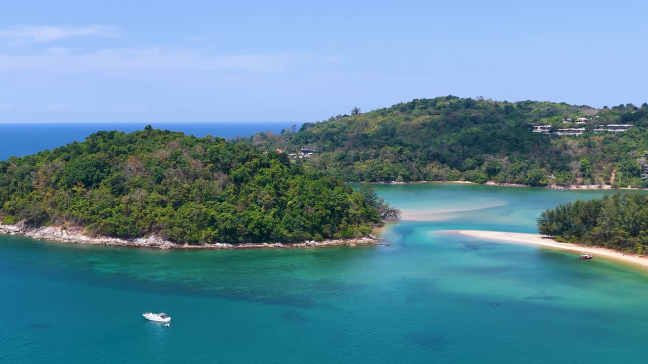Drone footage captures turquoise waters and lush green islands under a bright clear blue sky