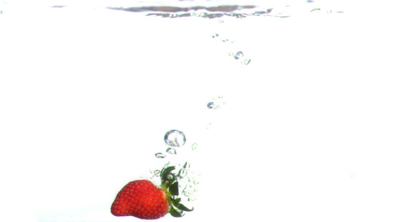 Strawberry falling into water in super slow motion
