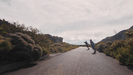 Junge-Frau-Reitet-Longboard-Freunde-Beim-Schlittschuhlaufen-Und-Hat-Spaß-Daran,-Auf-Einer-Wunderschönen-Landstraße-Bergab-Zu-Fahren,-Indem-Sie-Skateboard-Trägt-Und-Einen-Schutzhelm-Trägt