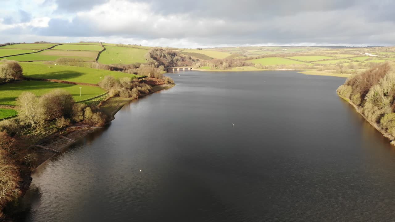 Aerial Over Calm Wimbleball Lake On Exmoor In Somerset Surrounded By Countryside. Dolly Right