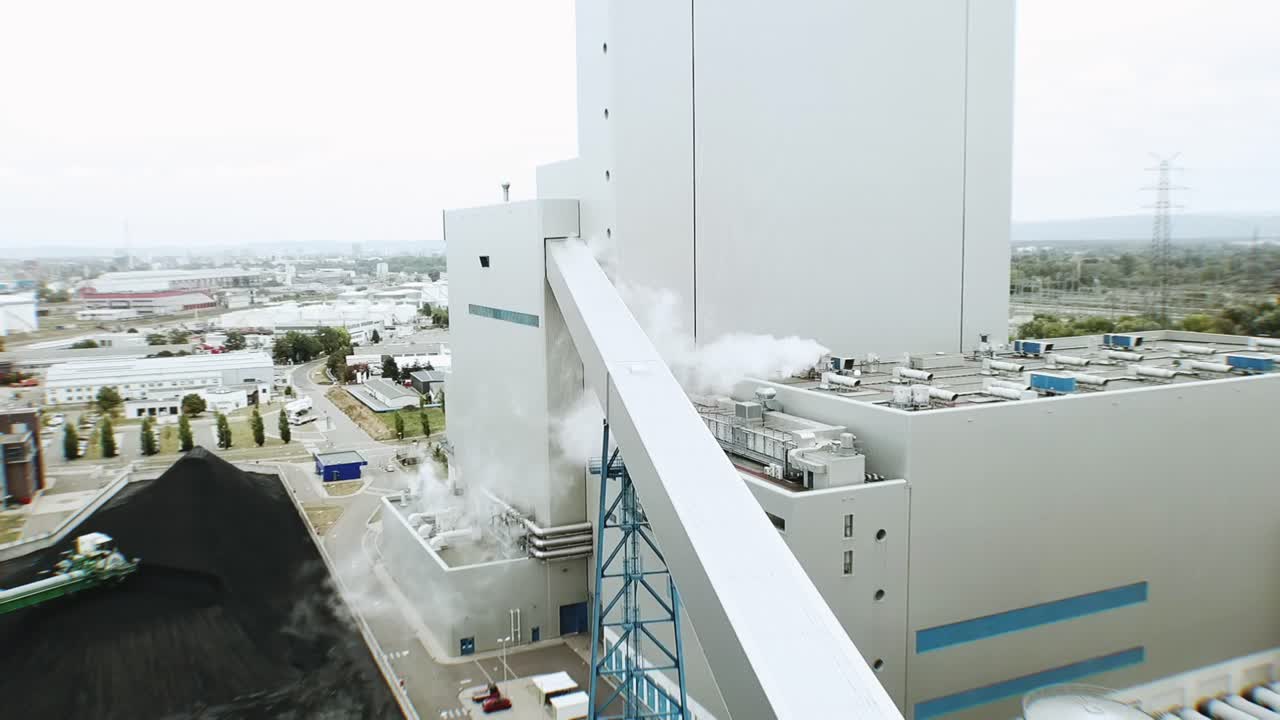 vuelo de drones hacia un edificio moderno en una central eléctrica de carbón europea con humo y cielos grises