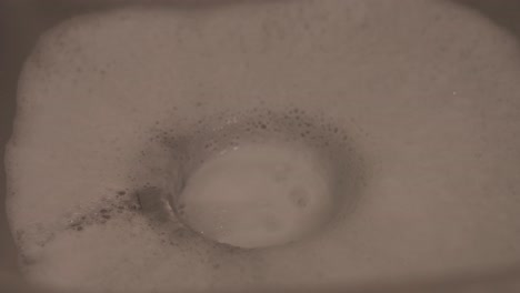 close-up shot of soapy water running down the sink as a person washes dishes, capturing a common household cleaning task.