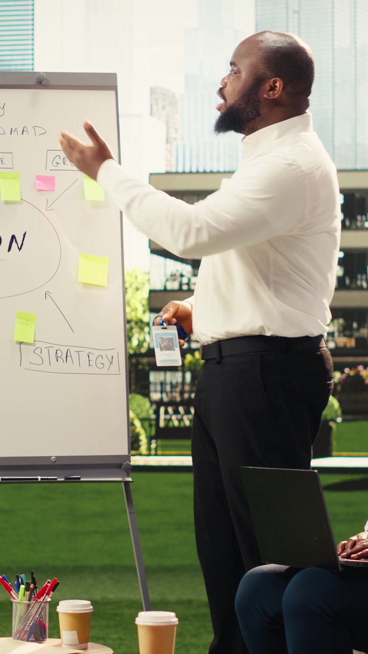 Video verticale. Presentatore afroamericano che indica una vision board con note adesive