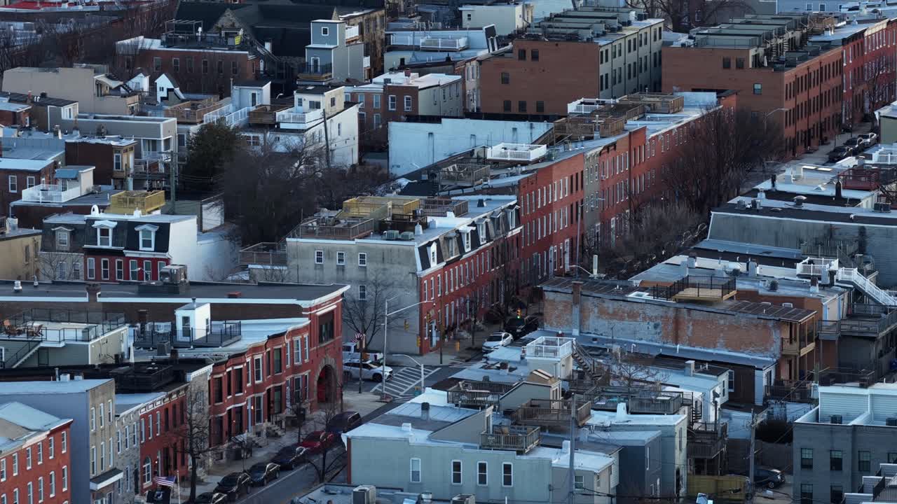 Flyfoto av et boligområde i Baltimore om vinteren. Snø dekker hustak og gater, og avslører tette rekkehus og urbane kvartaler under kaldt sesonglys i en amerikansk by. Vidvinkelbilde.