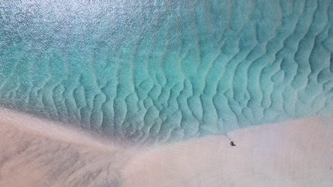 a crystal clear, blue lagoon revealing patterns in the sand caused by wave formations