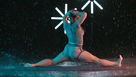 female caucasian dancer performing splits in the rain, slow motion effect