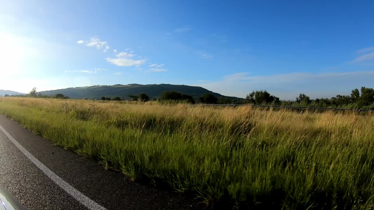 Driving on a highway or freeway with green natural background and a hill