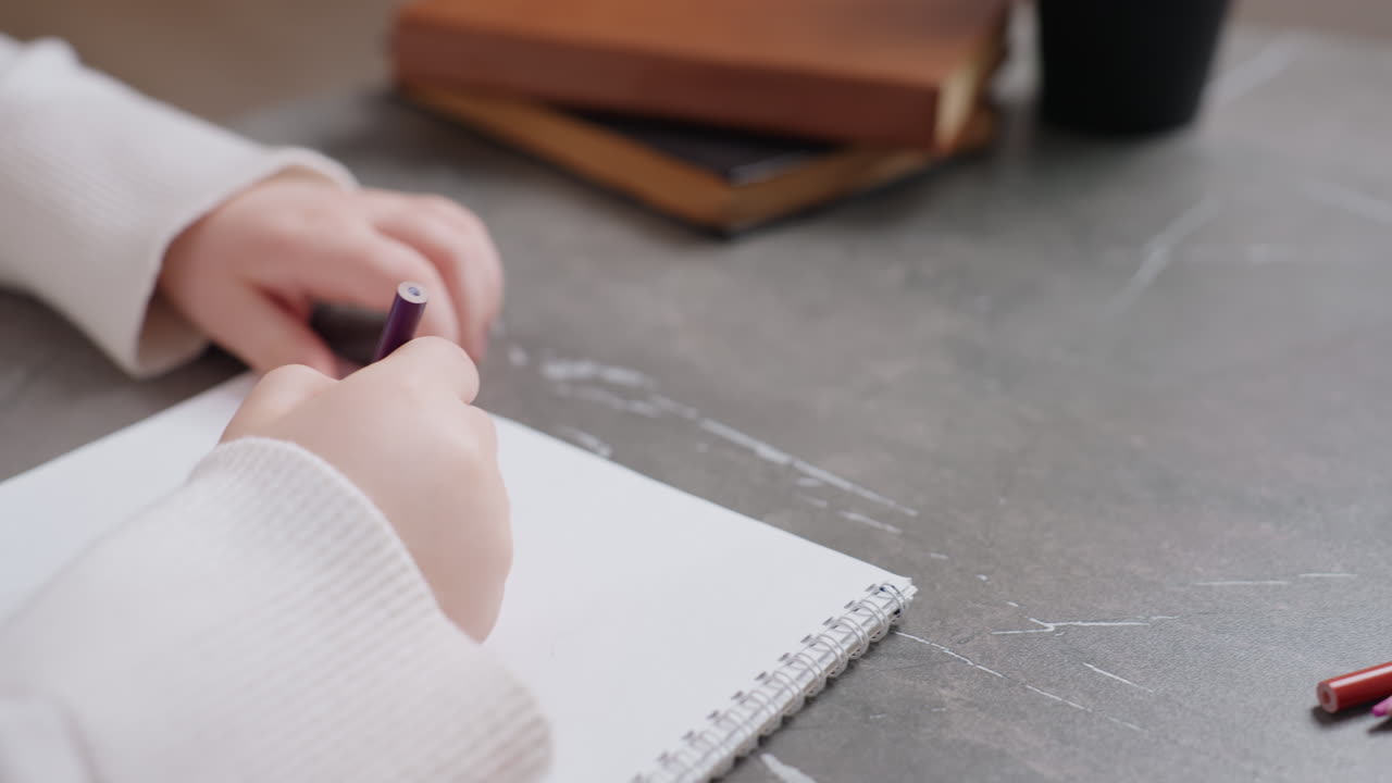 Hands of girl and parent with notebook on table during learning activity, showing creative education process with books, plant, guidance, and communication, highlighting support, and development