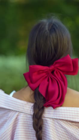 woman with red bow in a park