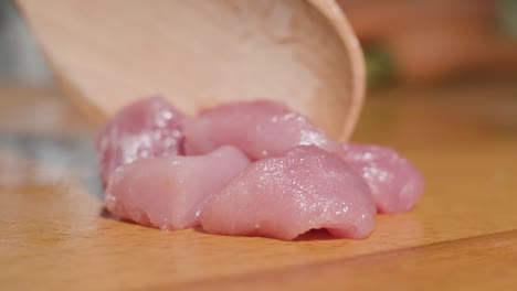 Super-Slow-Motion-Of-Uncooked-Young-Lamb-Meat-On-Chopping-Board-Pushed-By-A-Wooden-Spoon