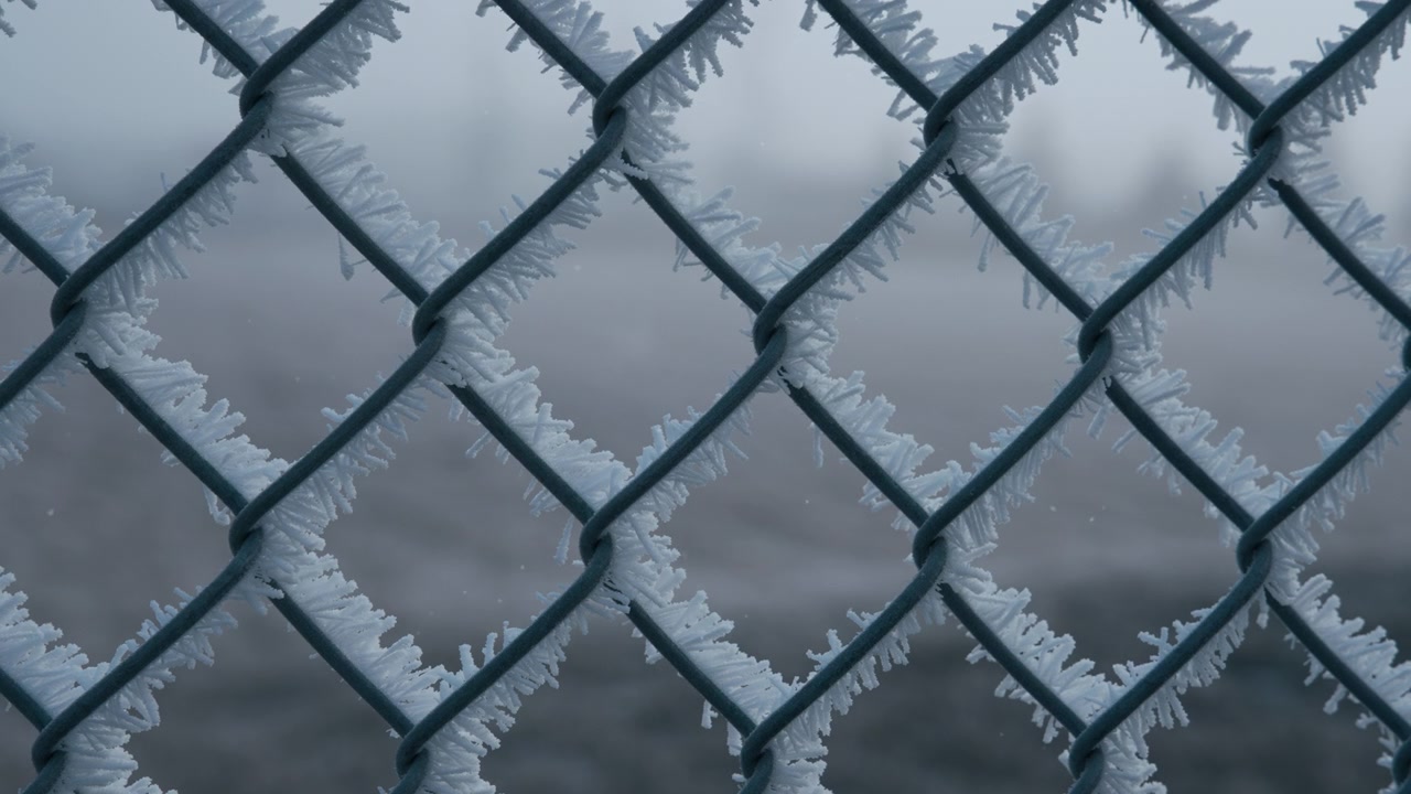 Metal fence covered in morning frost from freezing weather in winter